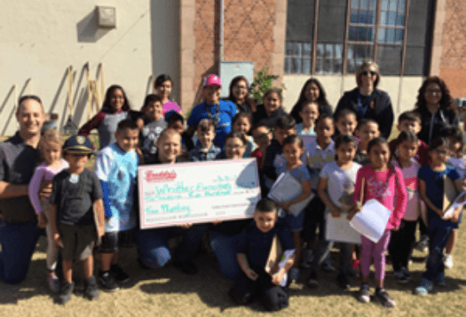 A group of Whittier Elementary School students and staff accepting a donation from Freddy's