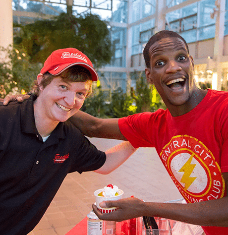 A Freddy's employee smiling with a customer who is holding his ice cream cup
